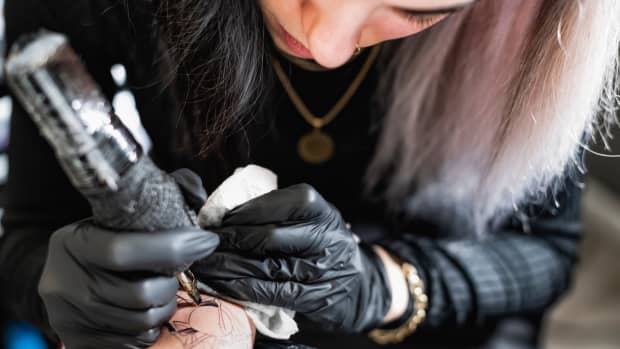 tattoo artist tattooing client's arm