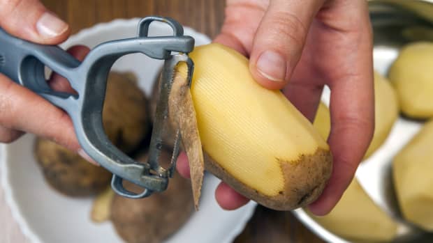 person peels the skin off a potato.