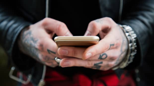 person with tattoos holding a phone in their hands.