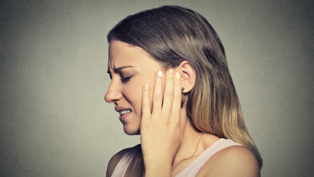 a woman holds her ear in pain