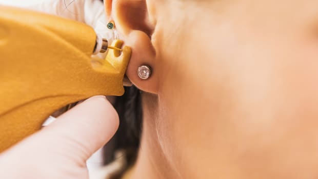 Woman getting her ear pierced with a piercing gun.