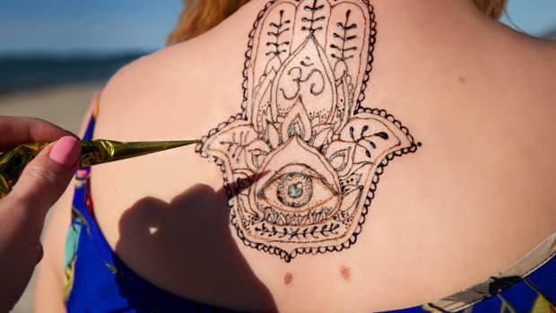 model gets a hamsa henna tattoo on their back.