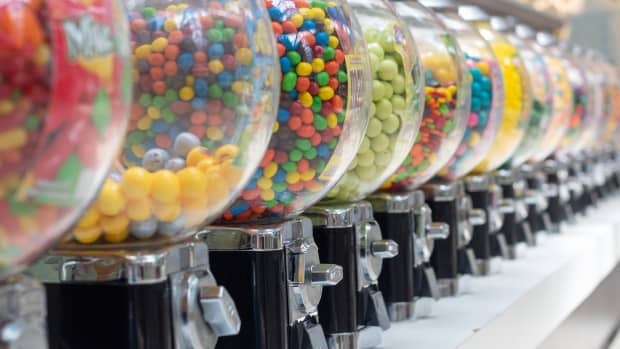 A row of different gumball machines filled with candy.