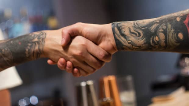 two people with tattoos holding hands.