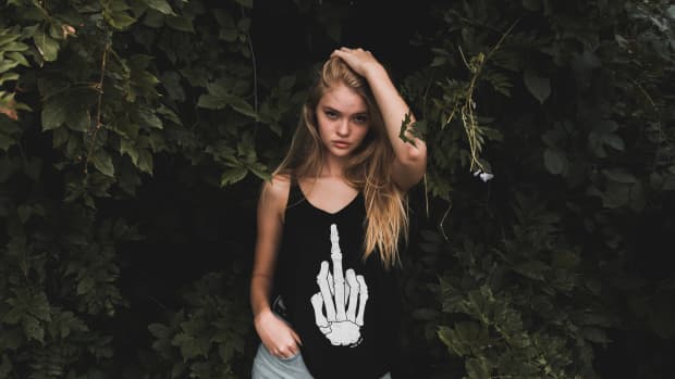 woman wears a shirt of a skeleton hand with its middle finger up.