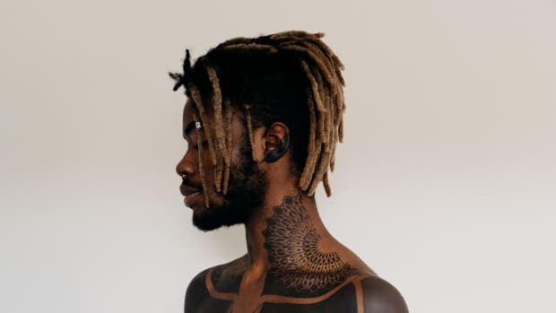 black man with tattoos on his neck, chest, and arms.